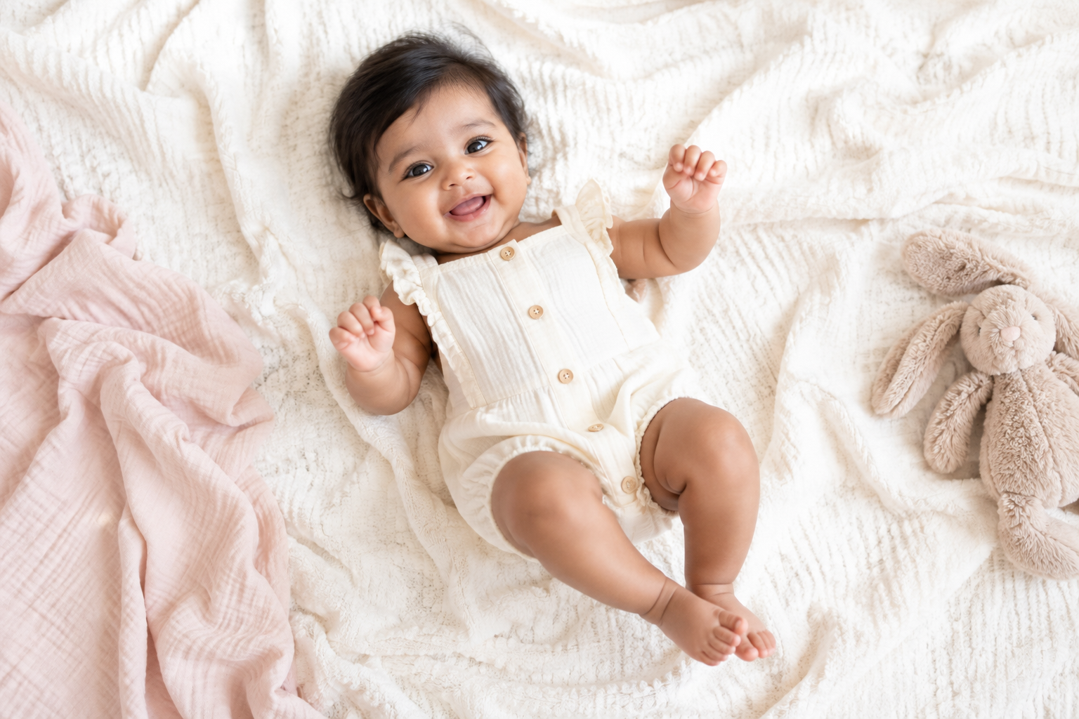 Baby smiling on a soft ivory blanket